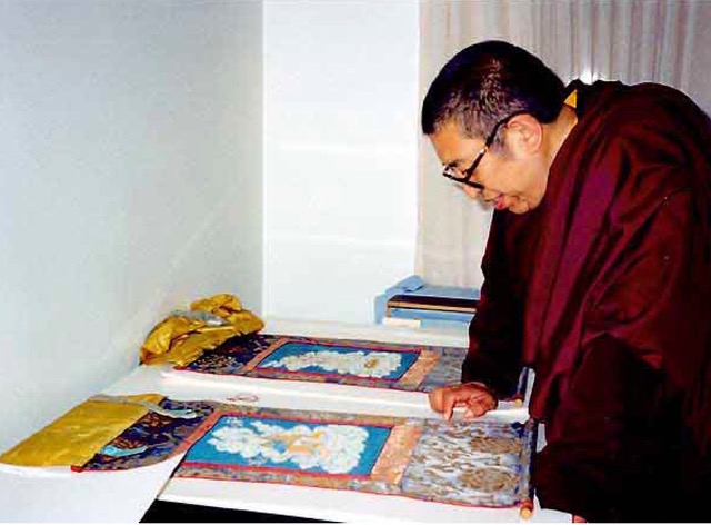 A Buddhist teacher looking at the two thangkas, still in their original textile mountings, in my studio, 1995. ©Ann Shaftel